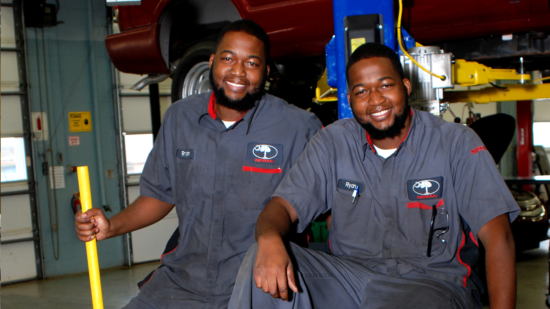 two auto tech students smiling in garage