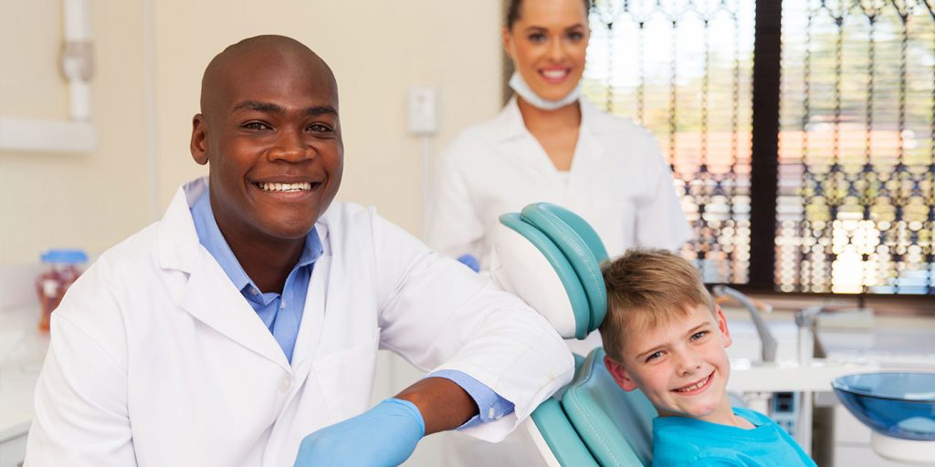 Dentist and dental assistant in office with child patient