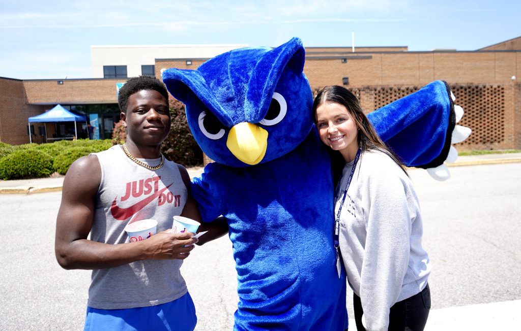 Male and female student smiling with mascot